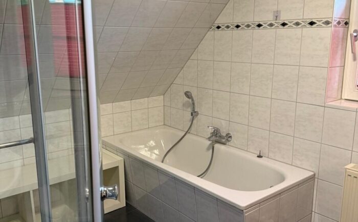 Bad mit Badewanne, Dusche und Fenster im Dachgeschoss